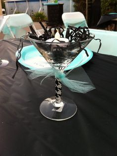 an empty martini glass sitting on top of a black table cloth covered dining room table