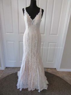 a white wedding dress on a mannequin in front of a door with a black dummy