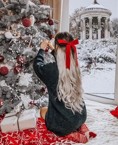 a woman sitting in front of a christmas tree