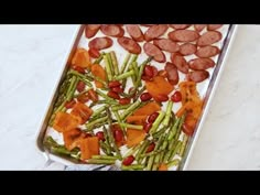 a pan filled with asparagus, sausage and other food on top of a table