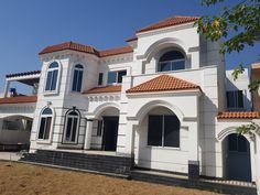 a large white house with red tile roofing and brown tiles on the front windows