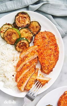 chicken, rice and zucchini on a plate with a fork next to it