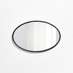 an oval mirror on a white wall with black trim around the edges and bottom edge