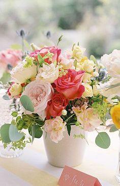 a vase filled with lots of flowers on top of a table next to a card