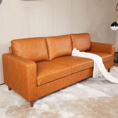 a tan leather couch with a white blanket on it