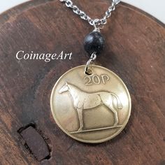 Irish Horse Coin Necklace -Irish Kilkenny Black Marble -20 Pence Domed Coin  -Celtic -Horse Pendant -Equestrian -Irish Jewelry Women  5048 A. The Irish 20 pence coin is made of copper, zinc and nickel which gives it a brilliant gold shine or soft brass color. The image of an Irish Hunter Horse is on one side with the Irish harp on the other. The coin is domed and the mint date is between 1985 and 2000. The Irish Hunter horse is an excellent sport horse, used in hunting, jumping, polo and fox hunting. It is a Thoroughbred. A polished Kilkenny Black marble stone connects the coin to chain. Kilkenny Marble is mined in Southeastern Ireland in Leinster Province.    CHAIN: Brilliant Stainless Steel Cable Chain 18 to 20 inch Adjustable Length with Lobster Claw Closure. CHAIN OPTION: Stunning .925 Celtic Horse, Irish Horse, Hunter Horse, Irish Harp, Horse Pendant, Celtic Necklace, Fossil Jewelry, Irish Jewelry, Horses Pendant