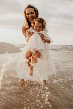 a mother and her daughter playing in the water at the beach during their wedding day