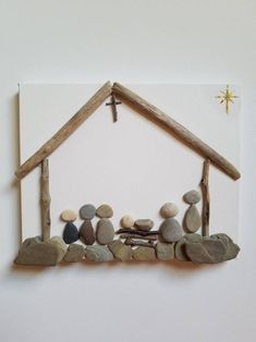 a nativity scene made out of rocks and wood with a star above it on a white wall