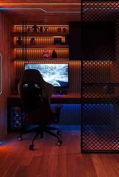 a room with a desk, chair and television on the wall is lit up by neon lights