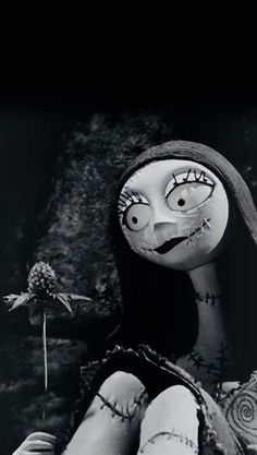 a creepy doll sitting next to a flower