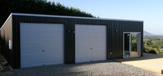 two garages with doors open on the side of a building in front of trees