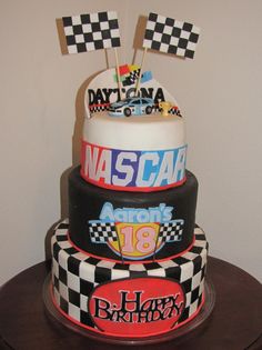 a three tiered birthday cake decorated with cars and race flags on top of it