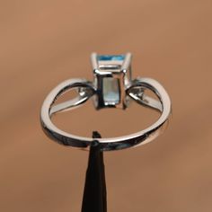 It is a Swiss blue topaz ring. The main stone is 6 mm*8 mm emerald cut.weight about 2.01 carats. The basic metal is sterling silver and plated with rhodium. To change the metal to a solid gold (white/rose) or platinum is also available, please ask for a quotation if you want. You can also go to my shop Home for more elegant rings: https://www.etsy.com/shop/godjewelry?ref=hdr_shop_menu Swiss blue topaz is November birthstone . More Swiss blue topaz rings: https://www.etsy.com/shop/godjewelry?ref= Formal Sterling Silver Topaz Ring With Rectangular Stone, Sterling Silver Topaz Ring With Rectangular Stone For Formal, Silver Emerald-cut Topaz Ring With Gemstone Accents, Fine Jewelry Blue Topaz Rectangular Rings, Silver Topaz Ring With Rectangular Blue Stone, Silver Topaz Ring With Rectangular Accent Stones, Silver Blue Topaz Ring With Rectangular Stone, Classic Blue Topaz Emerald Cut Ring, Classic Emerald Cut Blue Topaz Ring