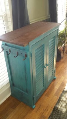 a blue cabinet sitting on top of a hard wood floor in front of a window