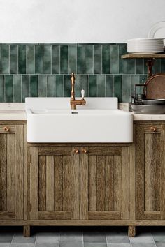 a kitchen with green tiled walls and wooden cabinetry next to a white ceramic sink