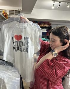 a woman looking at a t - shirt in a clothing store while holding it up to her ear