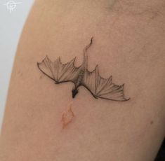 a leaf tattoo on the back of a woman's left arm, with an orange spot in it