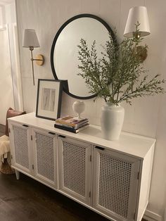 a white sideboard with some plants and pictures on it