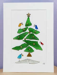 a christmas tree made out of green paper with birds and stars on it, sitting in front of a purple wall