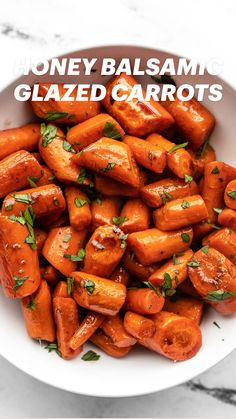 a white bowl filled with cooked carrots on top of a marble countertop and garnished with parsley