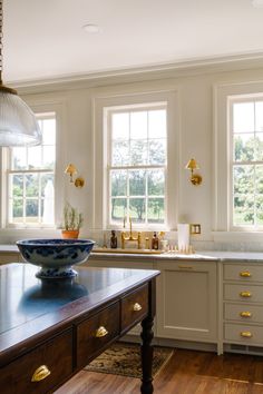 a bowl on a kitchen island in front of two windows with gold trimmings