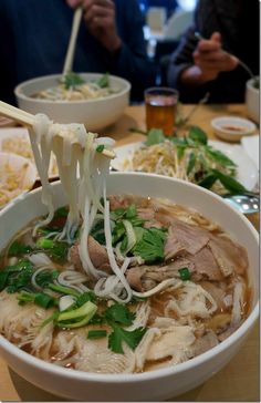 two bowls of soup with chopsticks sticking out of the noodles and meat in them