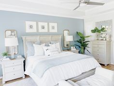 a bedroom with blue walls, white furniture and pictures on the wall above the bed