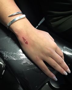 a woman's hand with a small red triangle tattoo on her left arm and wrist