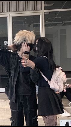 a man and woman kissing while holding cell phones