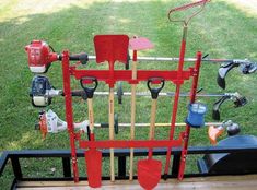 a red tool rack with tools on it in the grass