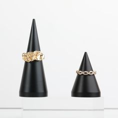 two rings sitting on top of each other in front of a black cone shaped object