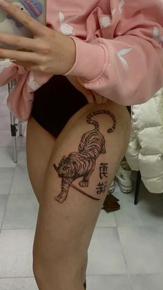 a woman with a tiger tattoo on her thigh is reading a book while sitting down