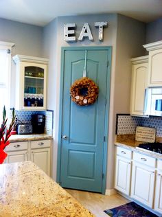 a blue door in a kitchen next to a counter top with a wreath on it