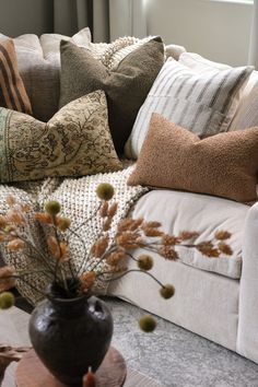 a living room filled with lots of pillows on top of a couch next to a window