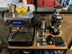 an espresso machine sitting on top of a wooden table next to other items