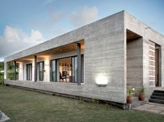 a house made out of concrete sitting on top of a lush green field