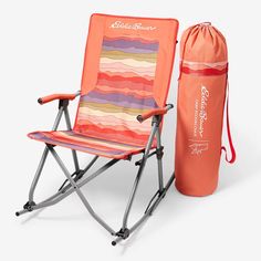 an orange folding chair next to a pink bag