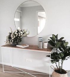 a mirror sitting on top of a wooden table next to a potted plant in front of it