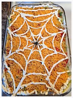 a spider web cake is covered in cheese and other toppings on a baking sheet