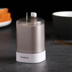 a toothpick dispenser sitting on top of a counter next to a bowl