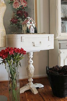 a vase with flowers sitting on top of a white table next to a mirror and potted plant