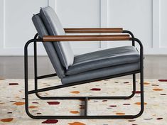 a gray leather chair sitting on top of a rug in front of a white wall