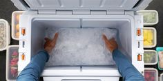 a person standing in an ice chest with their feet on the freezer door and food containers around them