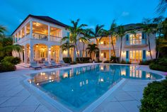 a large house with a swimming pool surrounded by palm trees