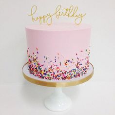 a pink birthday cake with sprinkles and the words happy birthday on top