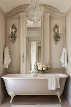 a white bath tub sitting next to a mirror and chandelier in a bathroom