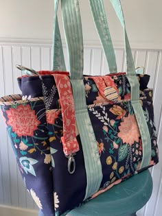 a large floral bag sitting on top of a blue chair next to a white wall