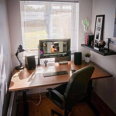 a desk with a computer monitor, keyboard and mouse on it in front of a window