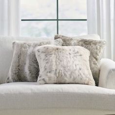 two pillows on a couch in front of a window