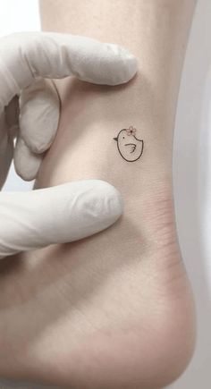 a person in white gloves holding up a small tattoo